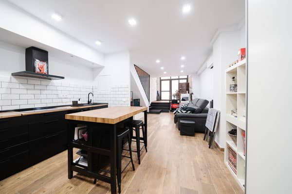 Cocina negra con isla central en cambio de uso de local a vivienda