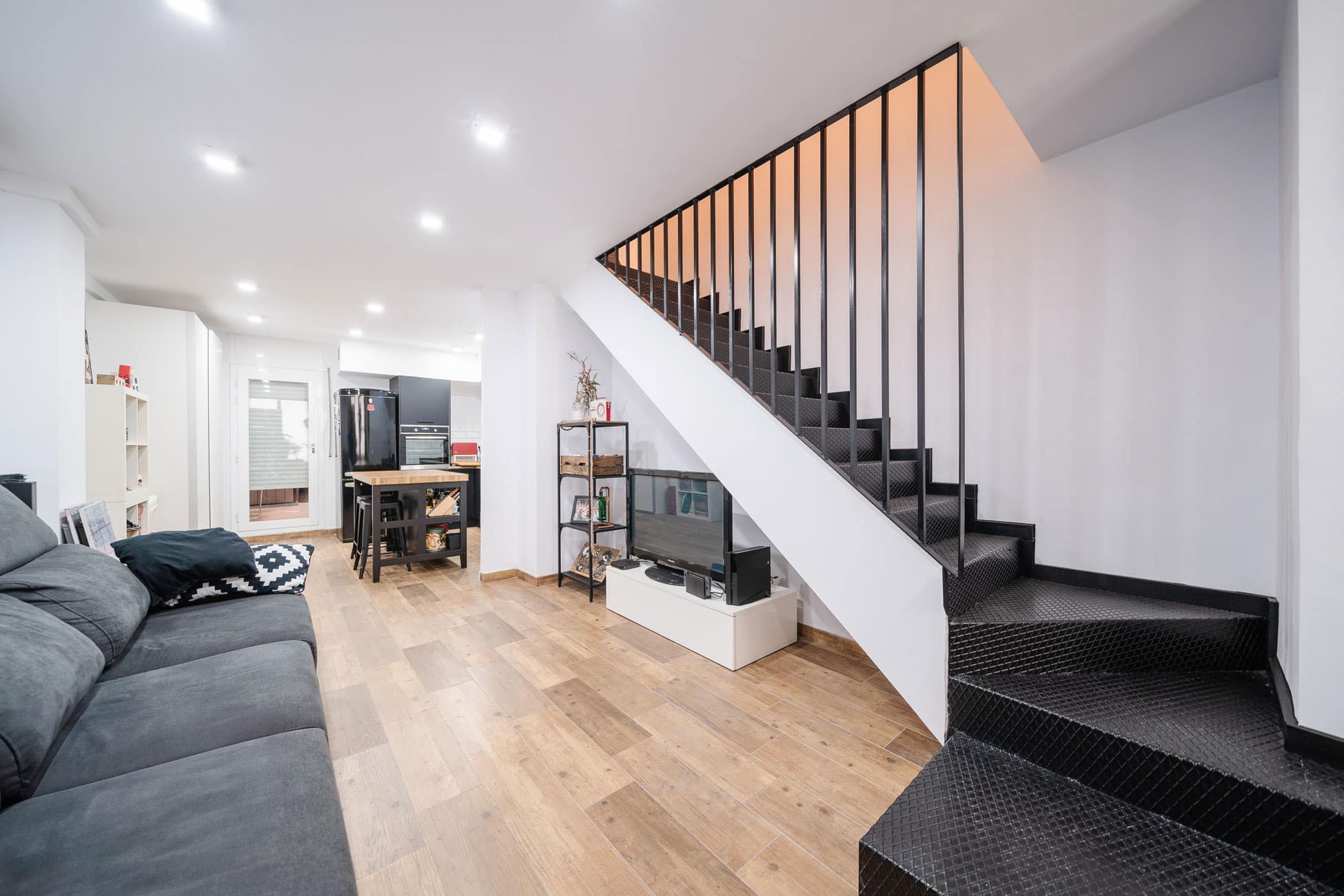 Salón con escalera negra en local convertido en vivienda dúplex