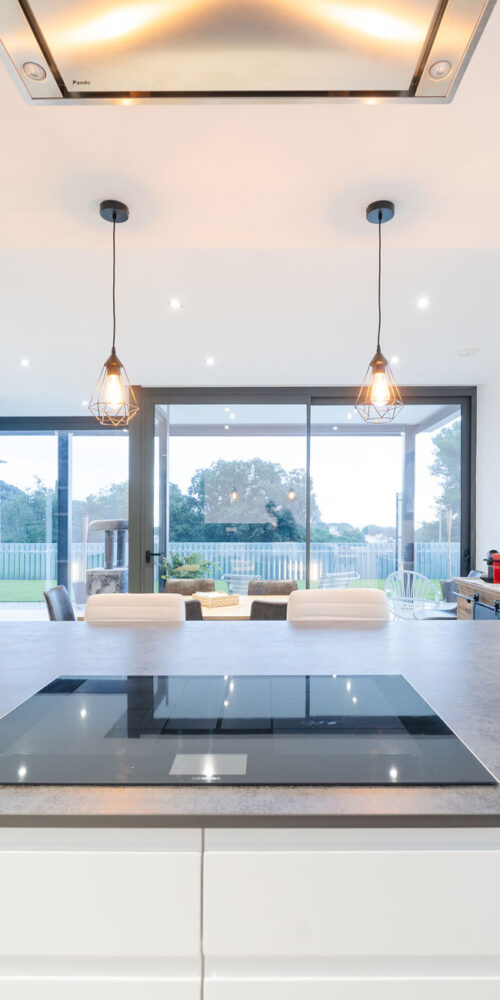 Cocina contemporánea con isla central, campana de techo y vistas al jardín de la vivienda MP17