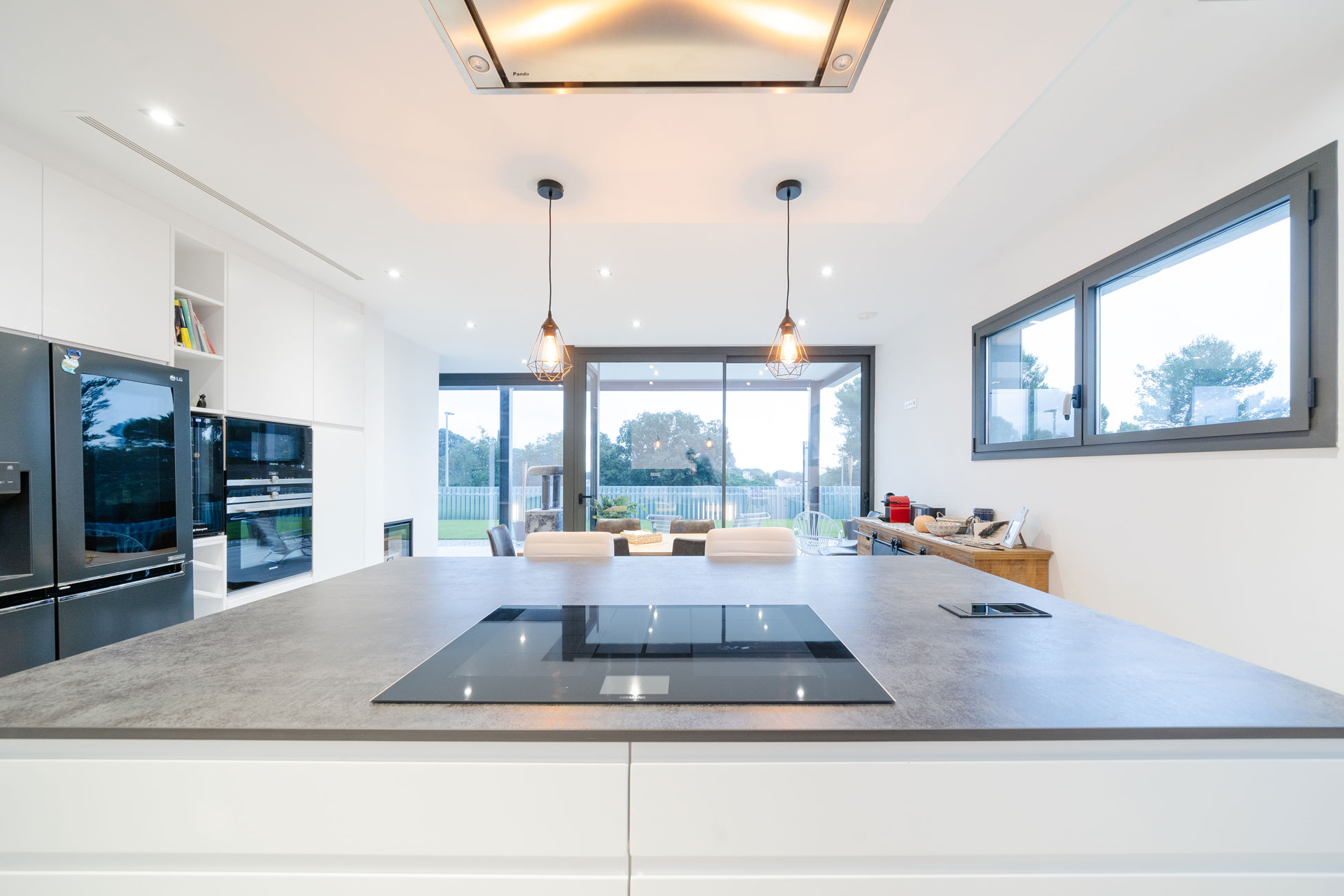 Cocina contemporánea con isla central, campana de techo y vistas al jardín de la vivienda MP17