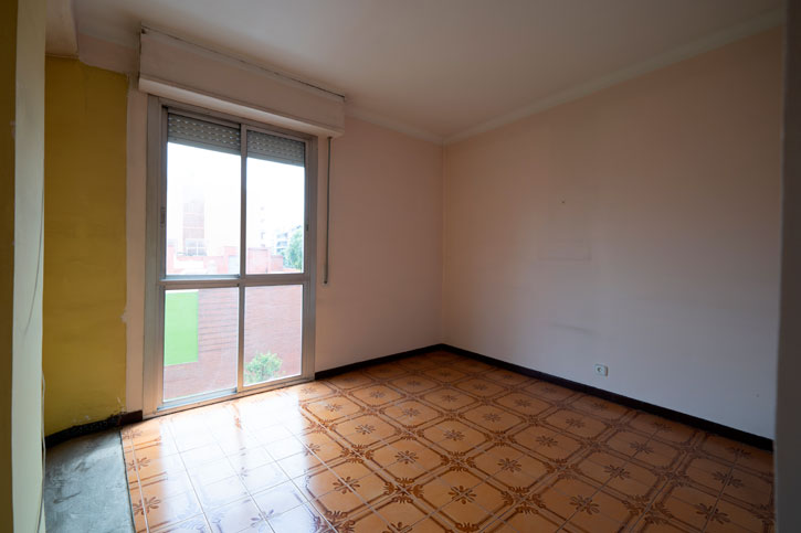 Dormitorio original con suelo cerámico marrón, paredes claras y gran ventana orientada al exterior.