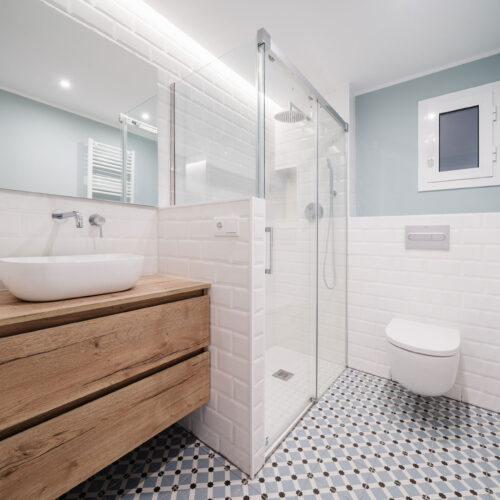 Baño reformado con mueble de madera y pavimento hidráulico en Barcelona.