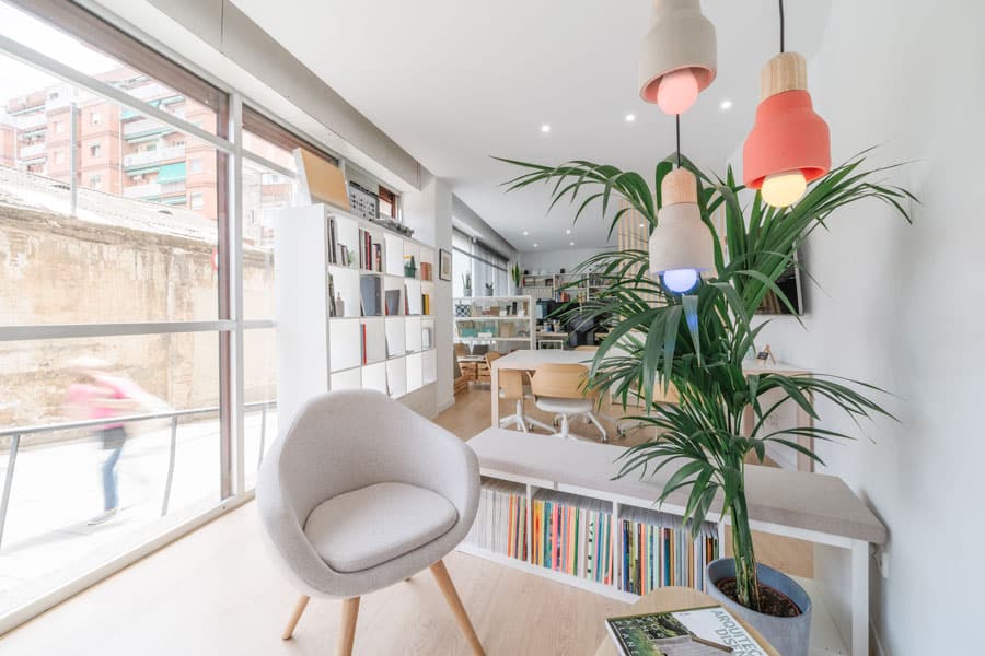 Zona de espera con butaca, vegetación y lámparas de colores junto al escaparate