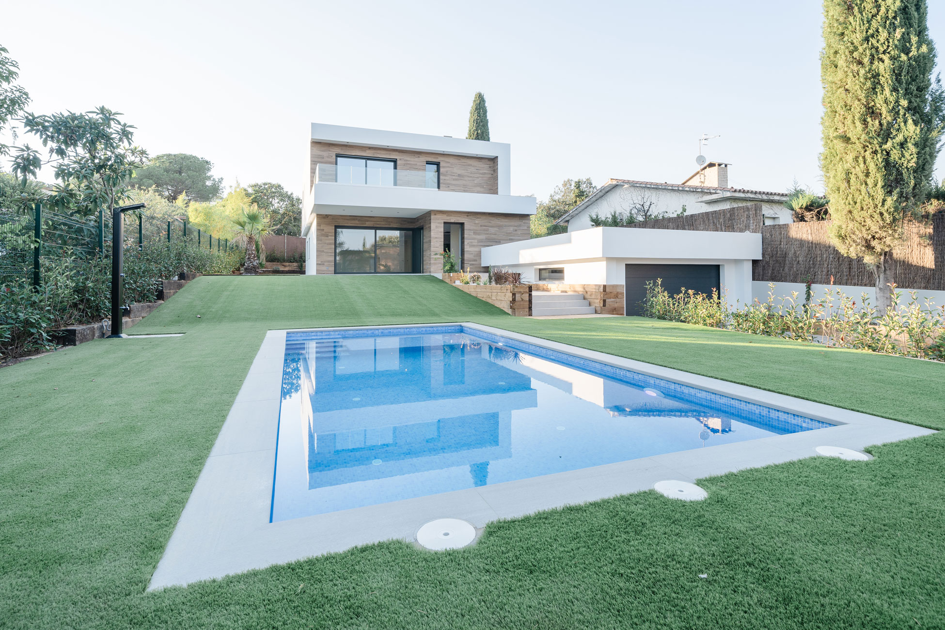 Casa moderna con piscina, jardín y garaje integrado en el desnivel